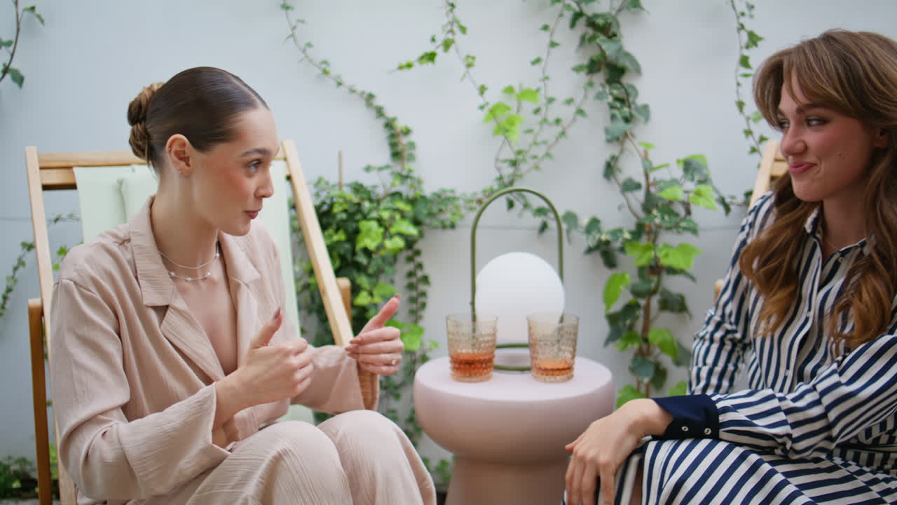 Joyful ladies discussing news talking animatedly sitting terrace smiling closeup
