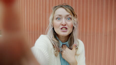 woman taking selfies in front of pink wall