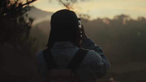 woman taking pictures at sunrise/sunset in the mountains