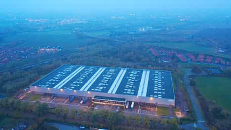 Aerial-shot-orbital-around-a-warehouse-at-night-,-circled-by-vegetation