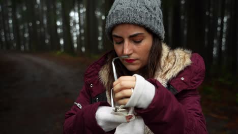 Woman-with-wool-hat-cleans-her-glasses-to-see-well-beauty-of-captivating-forest