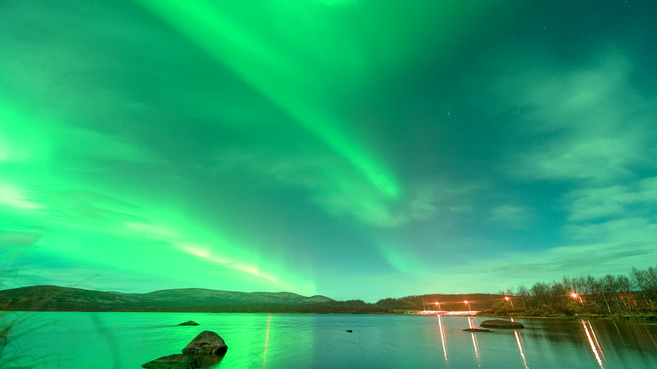 Luci verdi mistiche dell'aurora boreale danzano nel cielo notturno sopra il lago, timelapse