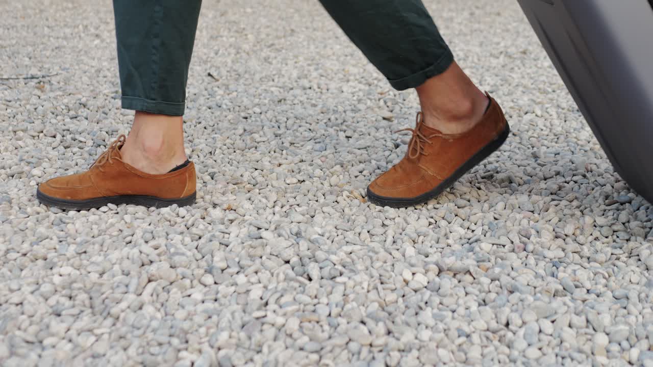 Person walking with a suitcase on gravel