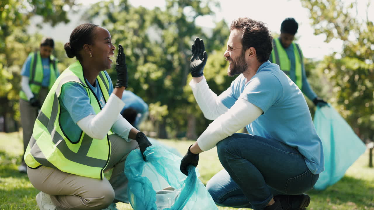 Happy Volunteers High-Fiving While Cleaning Up a Park