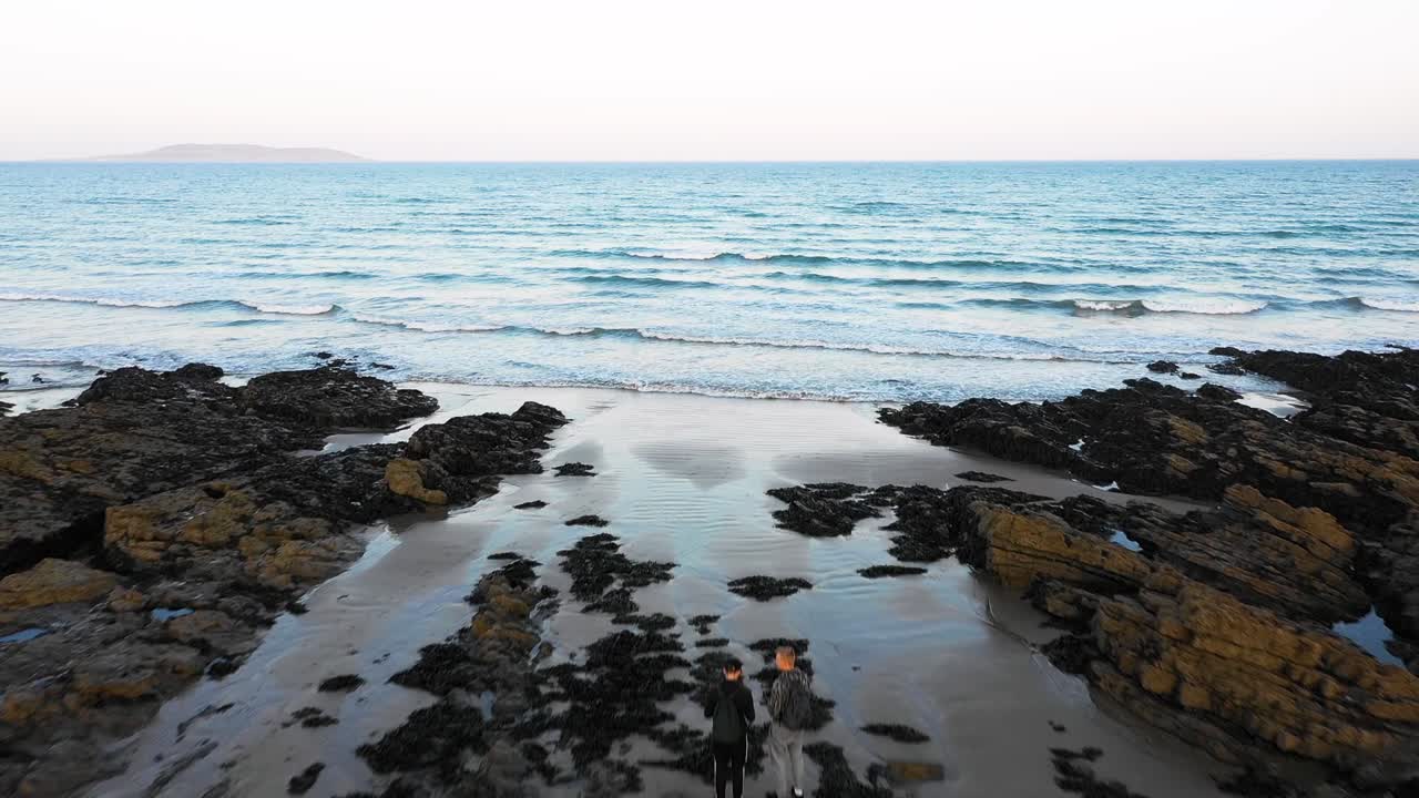 malahide의 바위 해변에서 두 젊은이