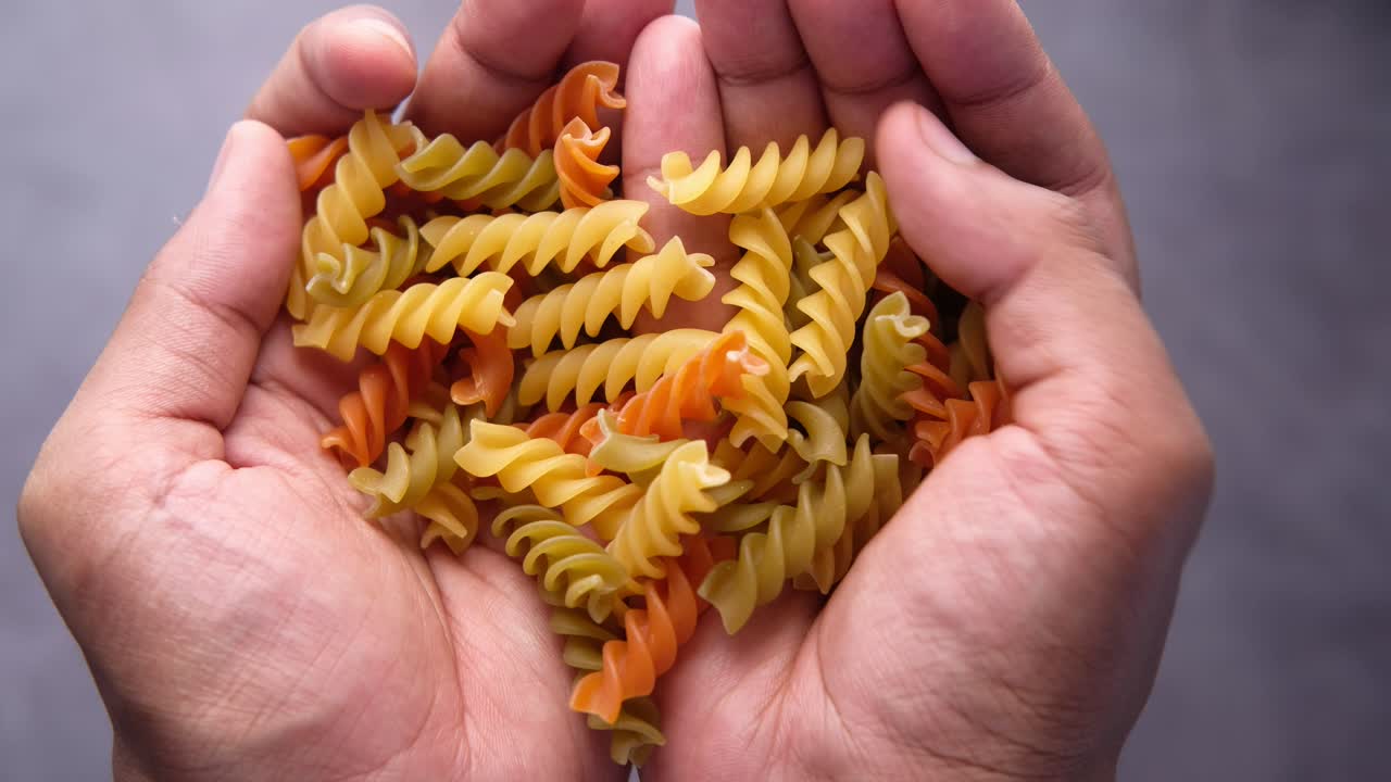 Hands Holding Colorful Spiral Pasta