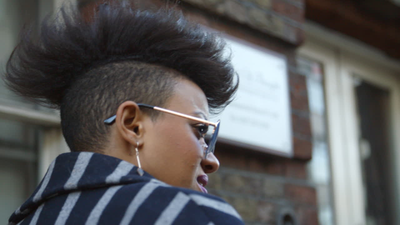 vista trasera de un elegante bloguero de moda caminando por una calle urbana