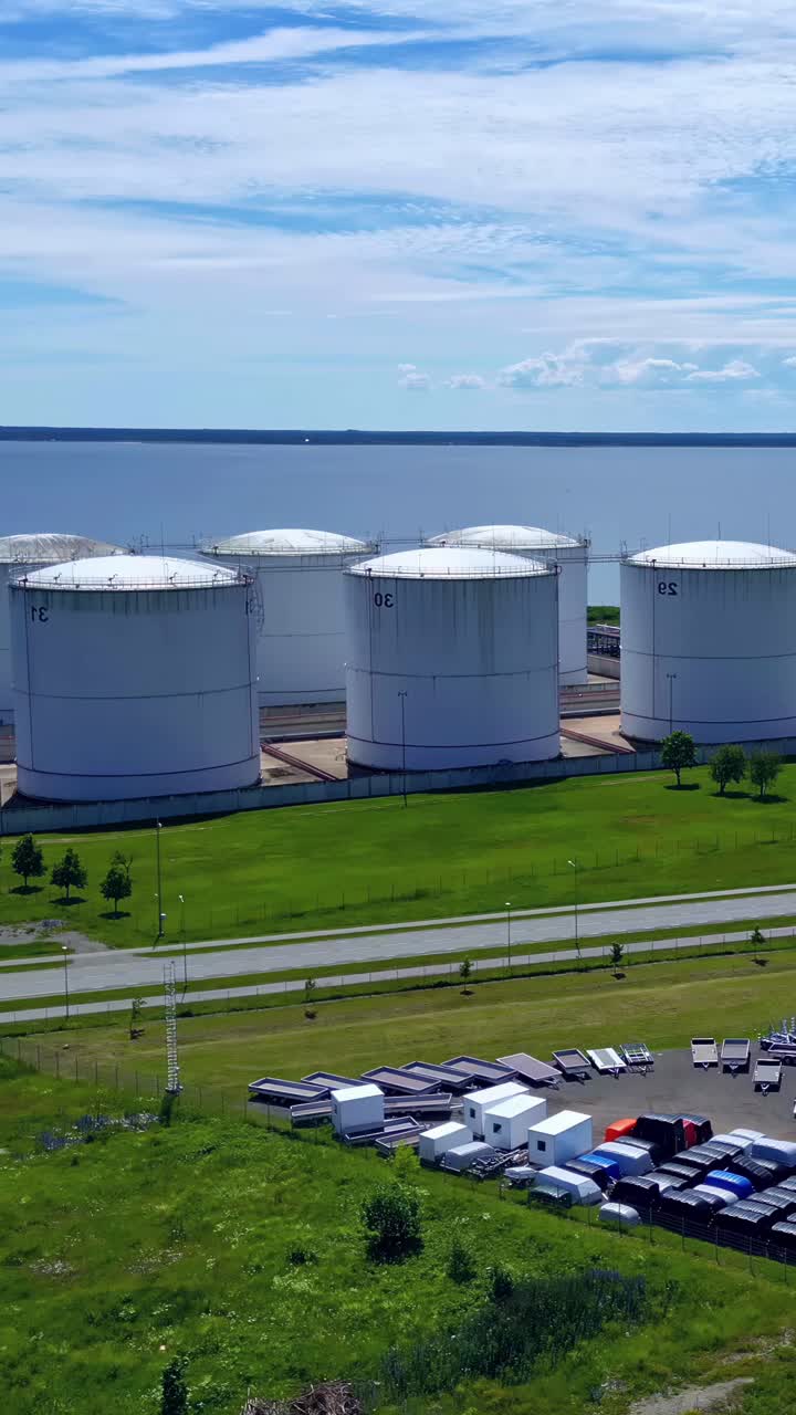 Large industrial tanks near a coastal area on a sunny day