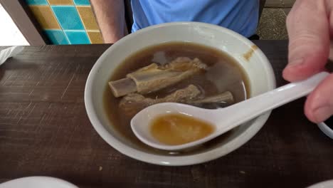 person eating bak kut teh soup with pork ribs