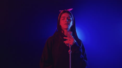 young woman singing into microphone on stage