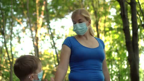 mother and child in medical masks walk in the park 03