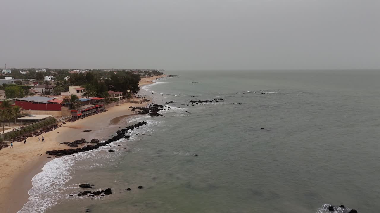 Drone footage of Somone beach, Senegal, showing golden sand, scattered rocks, and coastal houses near the calm Atlantic waters