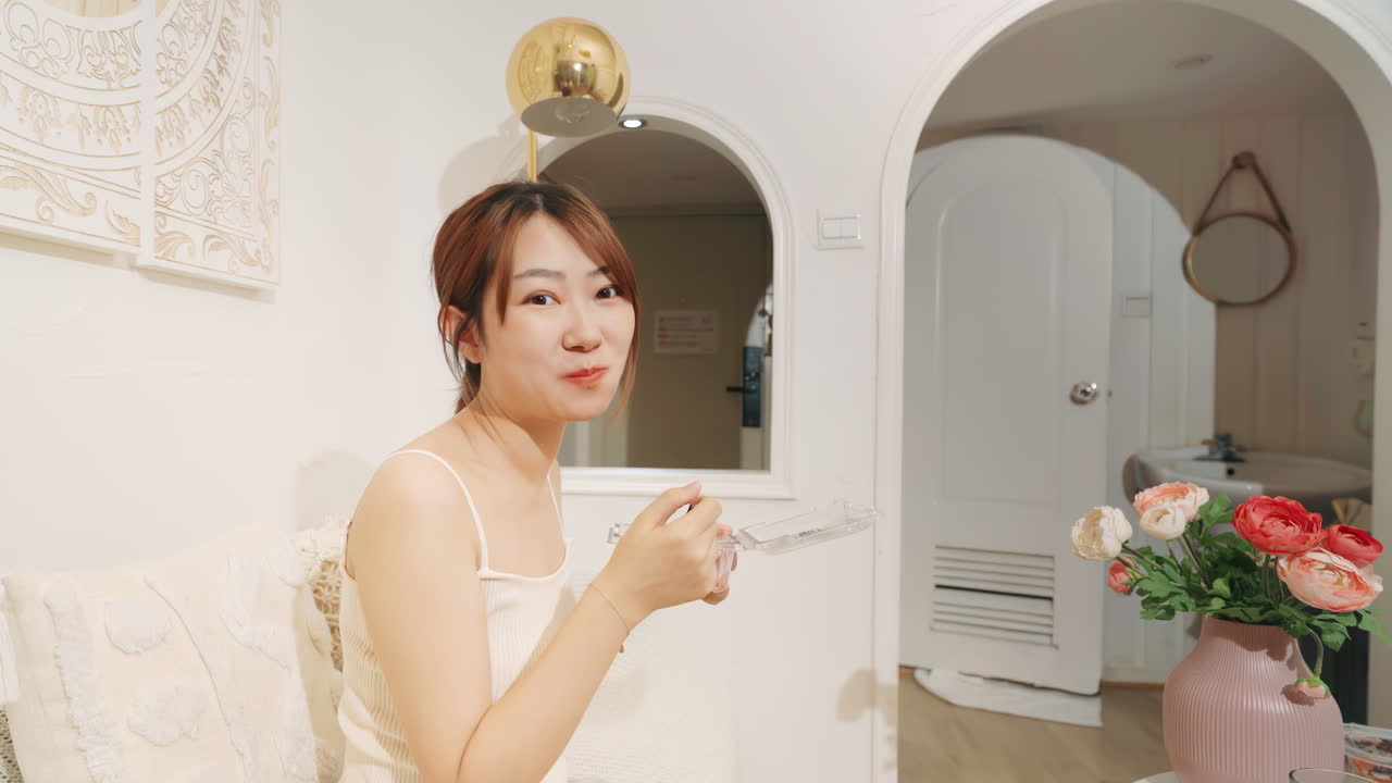 소파에서 초상화에서 과일을 먹는 여름 소녀의 실제, 아침 식사로 미소, 가정 거실에서 건강 다이어트, 비디오 시청