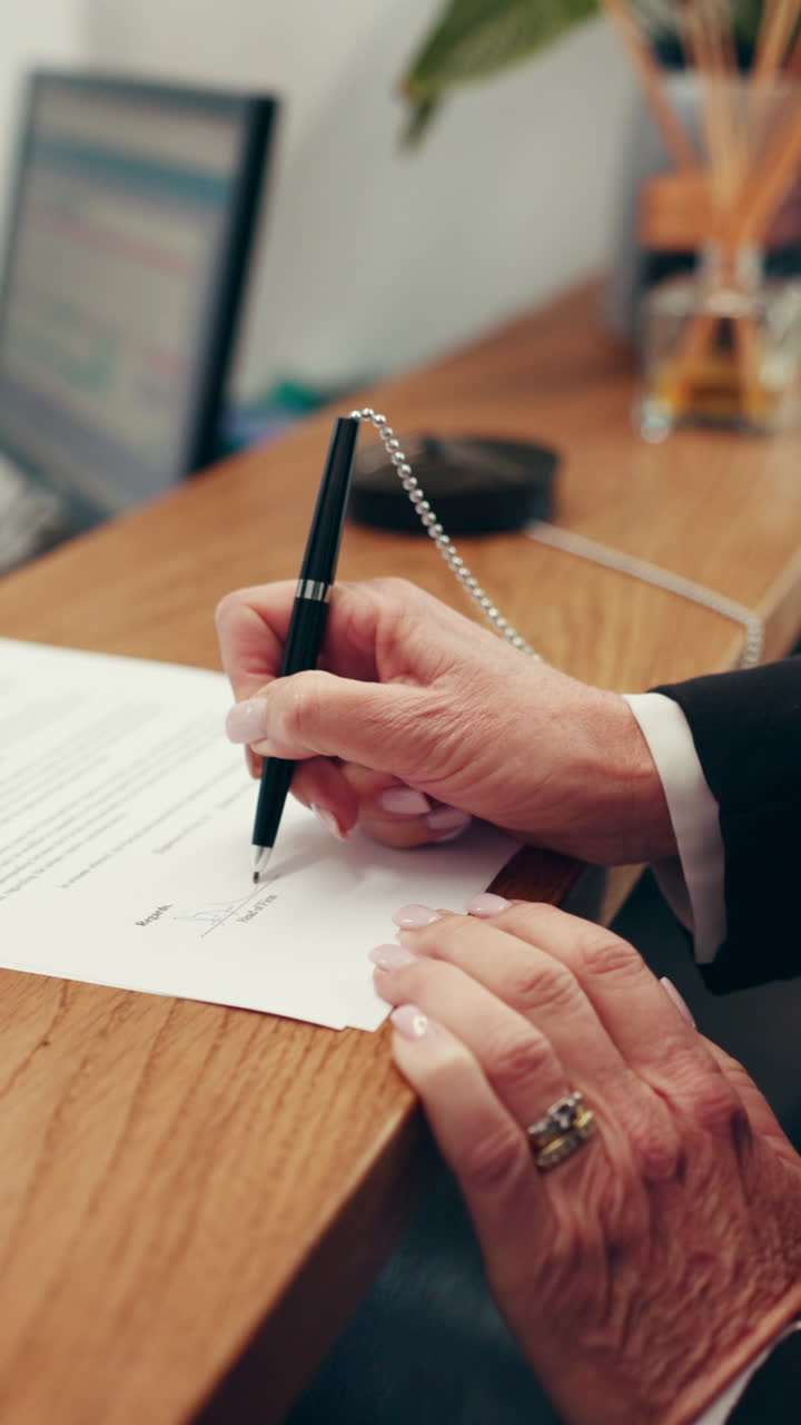 Primo piano di mani che firmano un documento su una scrivania di legno