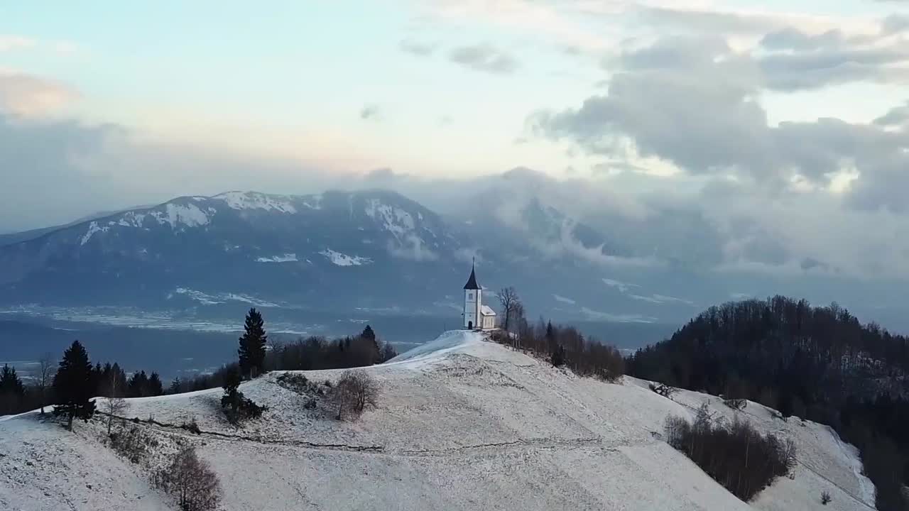 Vista della Chiesa di Jamnik in un paesaggio invernale con un'alba colorata a Kranj, Slovenia.