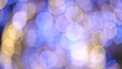 bokeh golden and blue lights of festive decorations moving on dark background