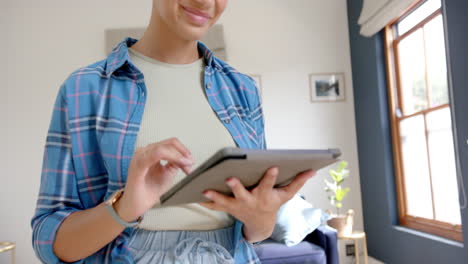 midsection of happy biracial teenage girl using tablet at home, copy space, slow motion