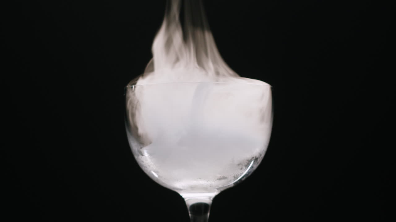 Dense White Smoke Swirling in a Glass on a Black Background