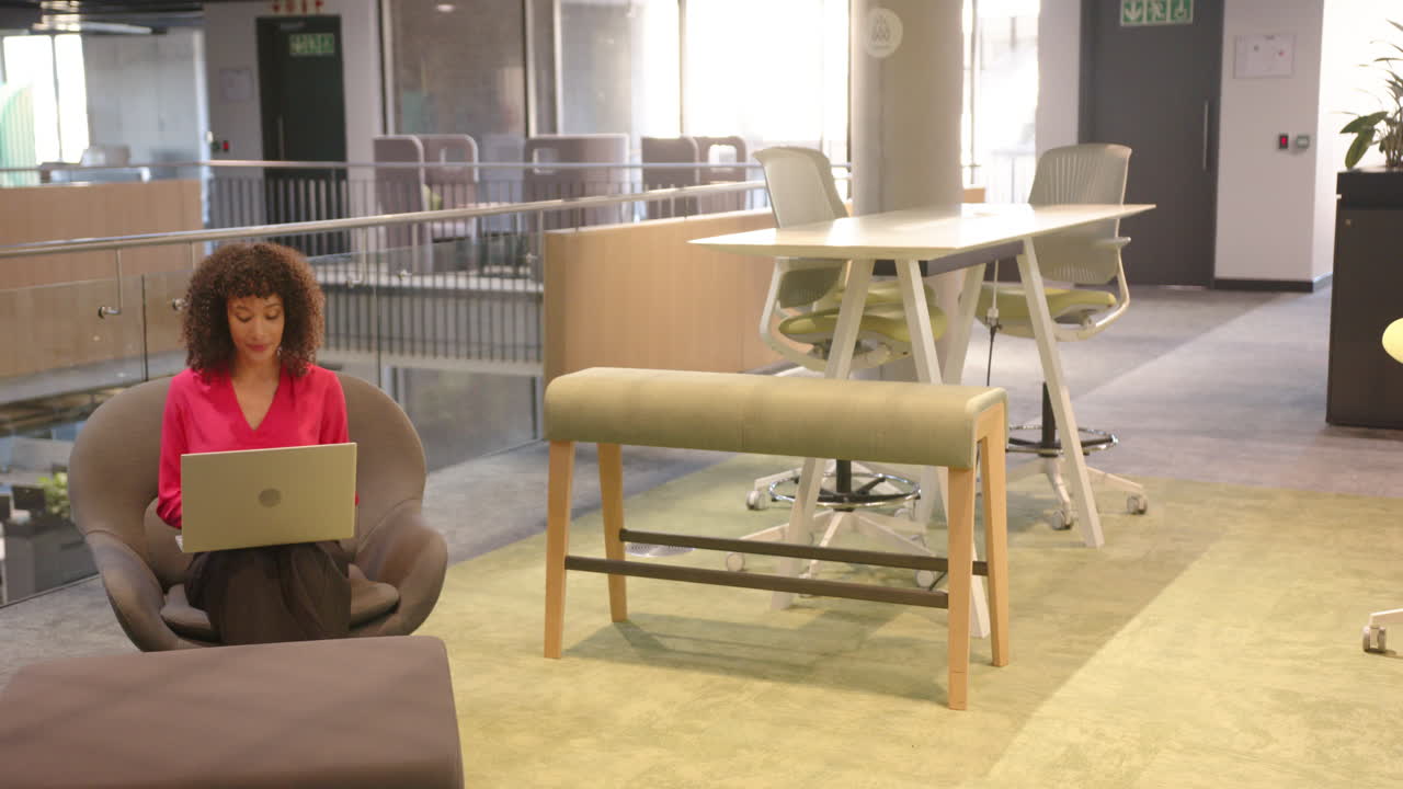 Working on laptop, businesswoman sitting in modern office lounge area