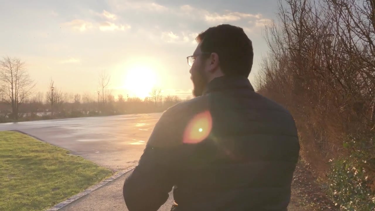 Ripresa in movimento di un giovane uomo barbuto che cammina per una strada francese vicino al tramonto