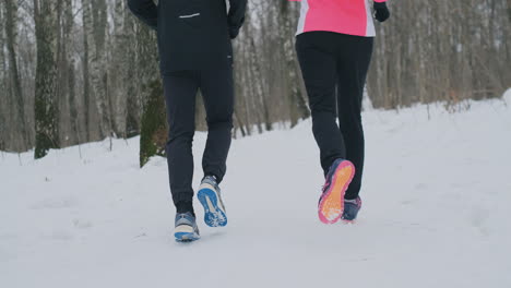 close-up of the feet of two runners in sneakers running in the winter in the park. the married couple goes in for sports.