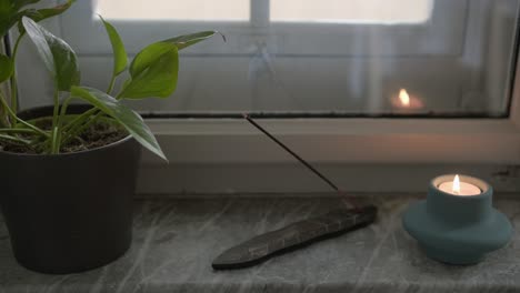 smoke form incense stick and relaxing candle next to living room window, yoga and meditation ritual