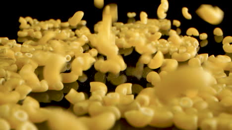 french pasta macaroni coquillettes falling on black table - slow motion