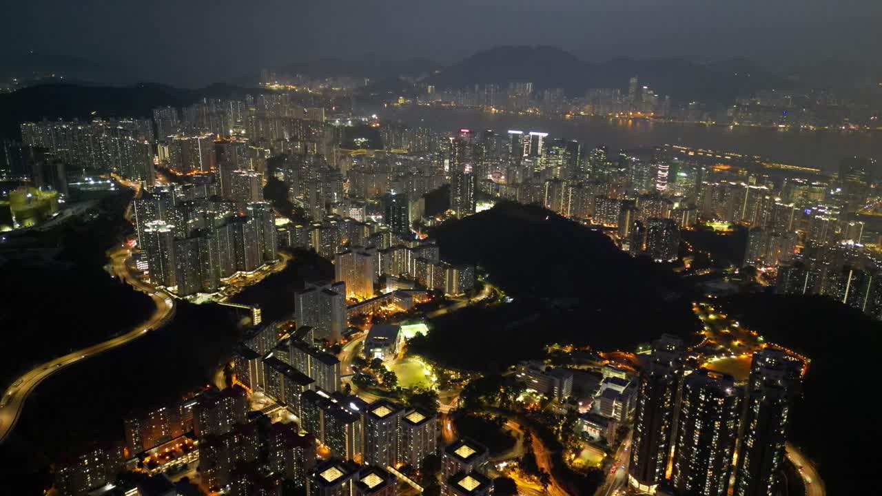 Aerial drone footage of Hong Kong city at night featuring illuminated skyscrapers, glowing skyline, and vibrant reflections showcasing the city’s modern architecture and lively urban beauty