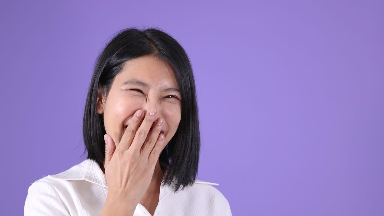 若い女性が手を振って、うれしそうに微笑んでいます。スタジオ照明、固定カメラ、鮮やかな紫色の背景。