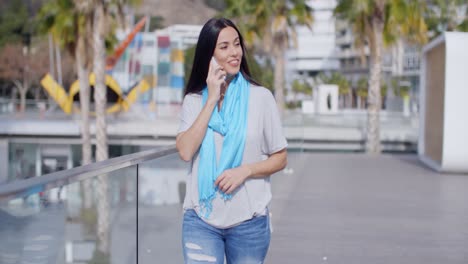 woman walking along a promenade with a mobile