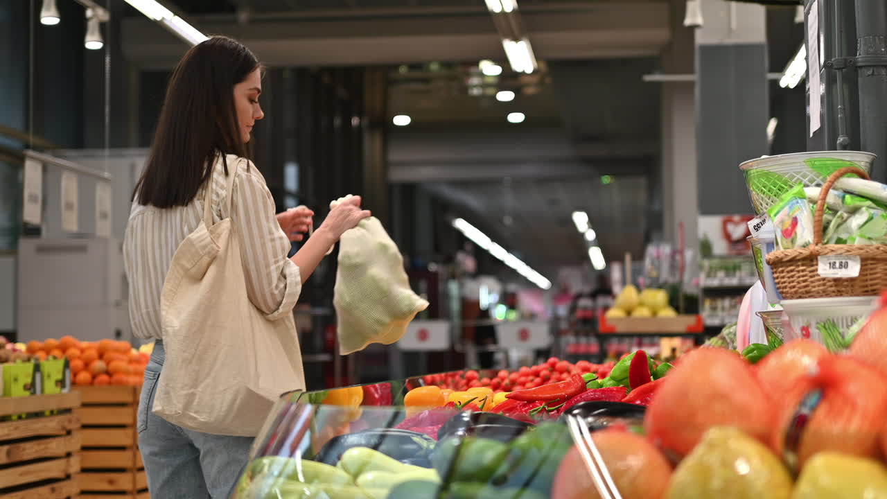 Mujer recogiendo pimientos en una bolsa reutilizable en una tienda. Temática de ecología y Día de la Tierra. Cámara lenta
