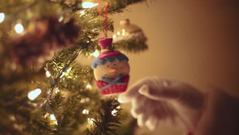 santa claus reaching to look at a snowman ornament