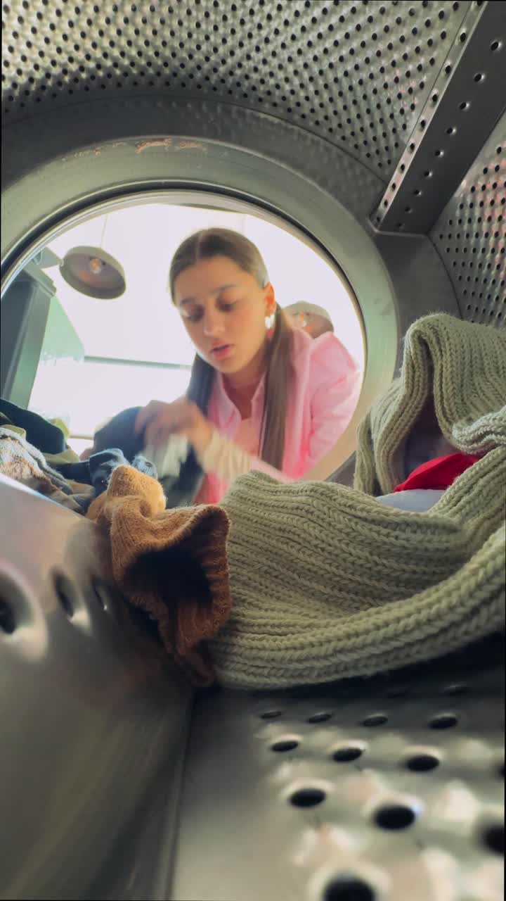 una adolescente haciendo la ropa dentro de una lavadora