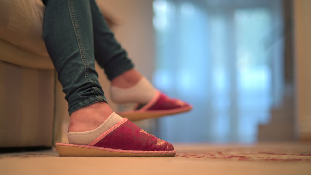 Close up of a woman's feet wearing slippers with a man walking on the background