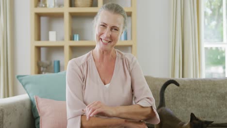 Portrait-of-happy-senior-caucasian-woman-sitting-and-making-video-call-with-cat-in-living-room