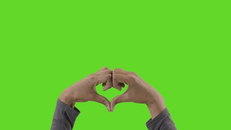 studio close up shot of woman making heart shape symbol for love against green screen 1