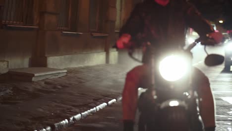 Stylish-motorcyclist-drives-a-bike-in-the-city-with-bright-headlight-at-night-by-street-in-fog