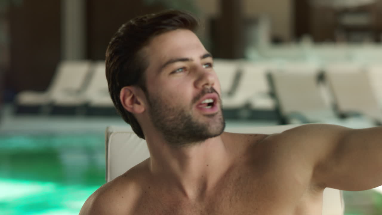 retrato de un hombre sexy posando para un video en vivo cerca de la piscina. tipo gracioso haciendo una selfie