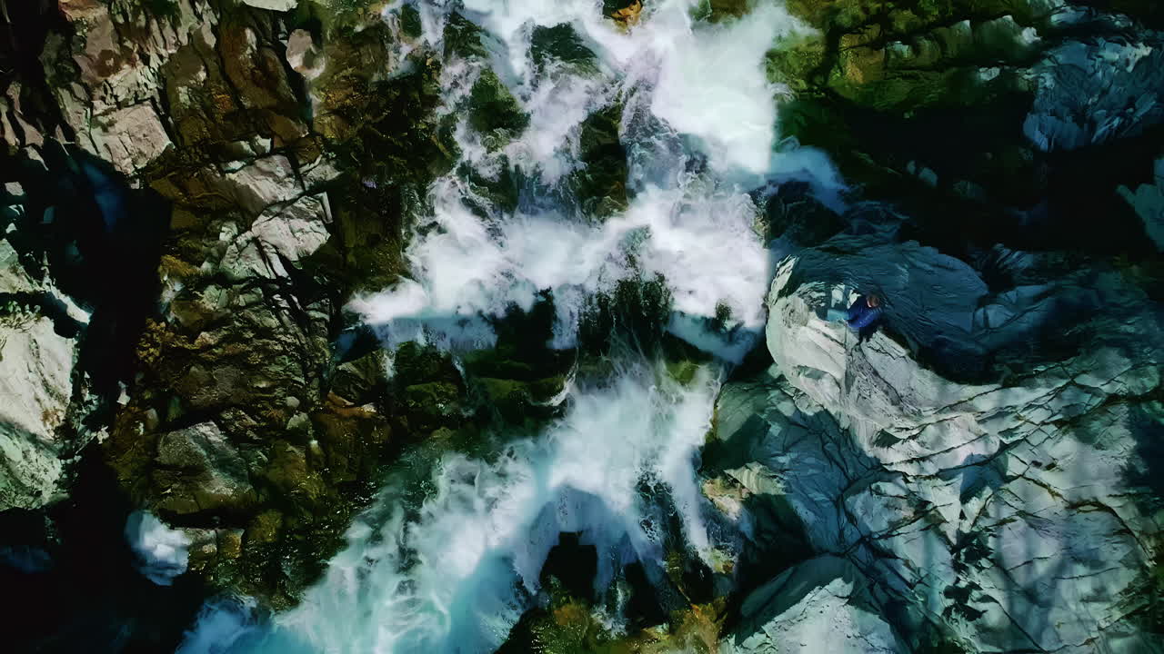 cascada cayendo por la ladera de una montaña en noruega - directamente hacia abajo ascendiendo aérea