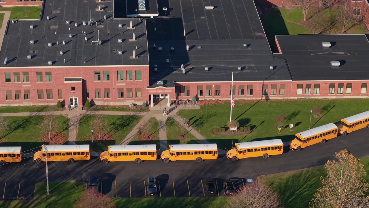 Dronebeeld van gele schoolbussen die wachten buiten een Amerikaanse school tijdens het uitgaan