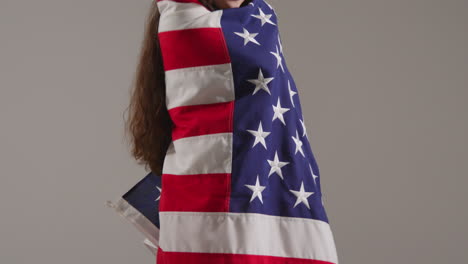 fotografía de estudio de cerca de una mujer envuelta en la bandera estadounidense celebrando el 4 de julio, día de la independencia.