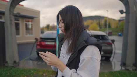 mujer cargando ev usando el teléfono
