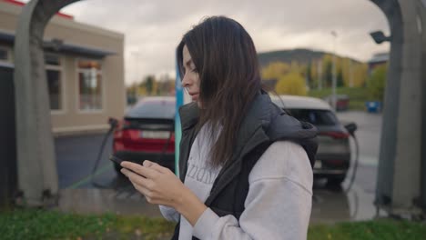 woman charging ev using phone