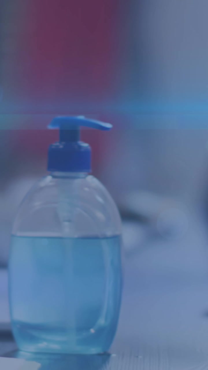 Scie di luce blu e la parte centrale di una donna che usa un disinfettante per le mani in ufficio
