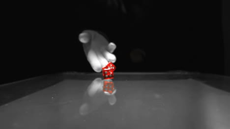 hand throwing two red dice onto table in black and white