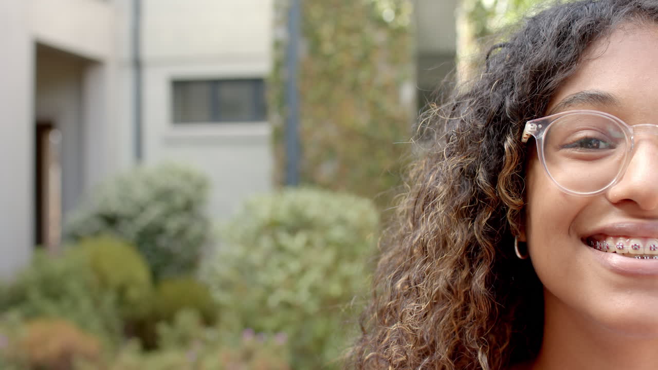 Teenage girl smiles outdoors, with copy space