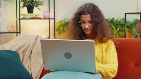 amazed teen girl use laptop computer, receive good news message, shocked by victory, celebrate win