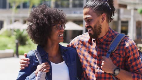 diverse couple walking on the street holding hands smiling and talking