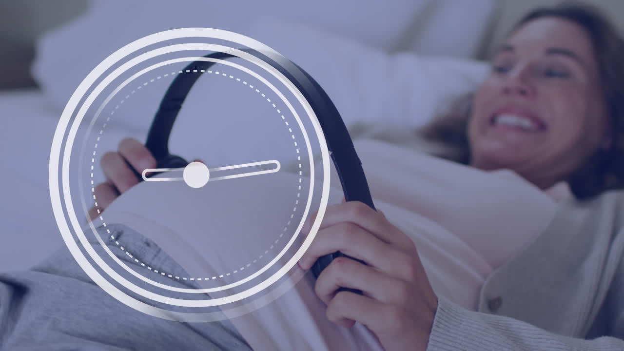 배 에 헤드폰 을 끼고 있는 행복 한 임신 한 백인 여자 위 에 빠르게 움직이는 손잡이 를 가진 시계