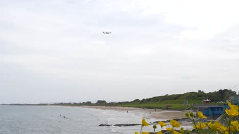 airplane flying above portmarnock velvet strand beach in dublin, ireland